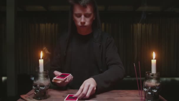 Feiticeiro misterioso concentrado cartomante masculino colocando cartões em ordem como rito místico. — Vídeo de Stock