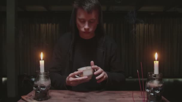 Концентрированный таинственный волшебник мужской гадалка держит чашку кофе и читать судьбу — стоковое видео