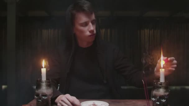 Soustředěný tajemný kouzelník muž věštkyně zapálí červenou svíčku, dá ji na talíř v magickém rituálu — Stock video