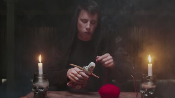 Soustředěný tajemný kouzelník muž věštkyně používá voodoo panenku a červené lano k hroznému magickému rituálu — Stock video