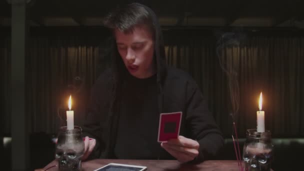 Soustředěný tajemný čaroděj muž věštkyně používá tarot kartu a tablet číst budoucnost — Stock video