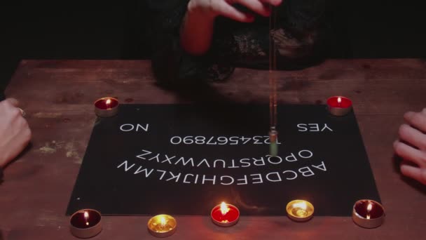 Bovenaanzicht van heks vrouwelijke waarzegster probeert te spreken met geest. Twee vrouwen en één man gebruiken Ouija Board Spirit Game — Stockvideo