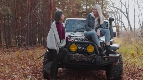 Two young women girlfriends with a white car in autumn forest — Stock Video