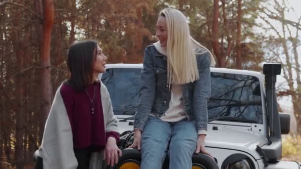 Two young women girlfriends with a white car in autumn forest — Stock Video