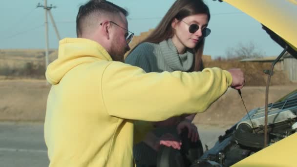 Giovane coppia insieme controlla l'olio in macchina in camper in un viaggio su strada — Video Stock