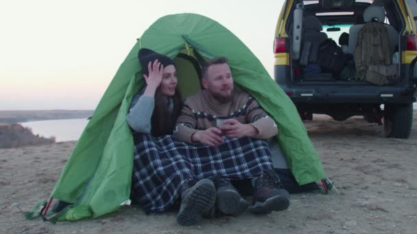 Young man and woman sitting near the tent and the car in the mountain during sunny day. — Stock Video