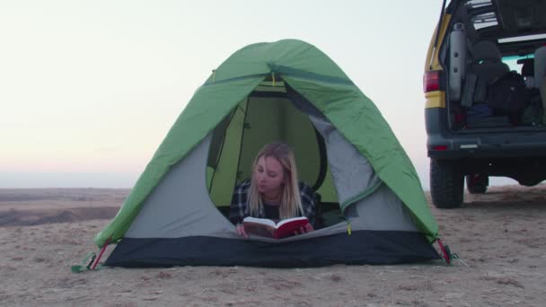 Jeune femme couchée dans la tente et lire le livre sur la montagne — Video