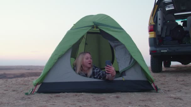 Young woman lays in the tent and records self video on phone on the mountain — Stock Video