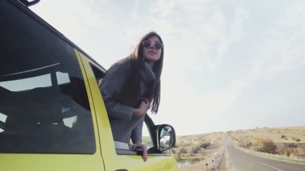 Jeune femme avec longue entendre penché par la fenêtre de la voiture — Video