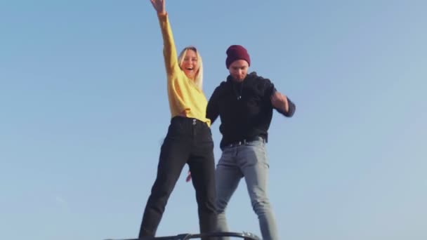 若いカップルは秋のロードトリップ中にヴィンテージバンの屋根で楽しみを持っています — ストック動画