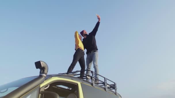Jeune couple prend selfie sur le téléphone sur le toit d'un van vintage lors d'un voyage d'automne — Video