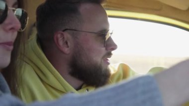 Hoş bir çift arabada oturur, gülümser ve konuşur.