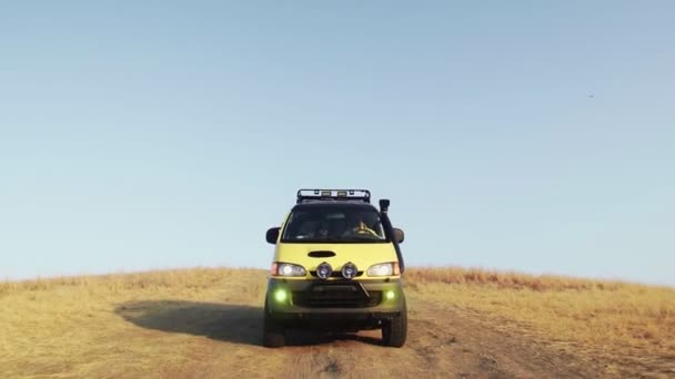 Żółci obozowicze van jedzie off-road w letni ranek — Wideo stockowe