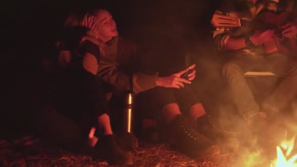 Deux jeunes femmes prennent des photos selfie au téléphone pendant que leurs amis chantent des chansons et jouent de la guitare. — Video