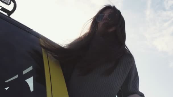 Jeune femme avec des lunettes de soleil penché par la fenêtre de la voiture — Video