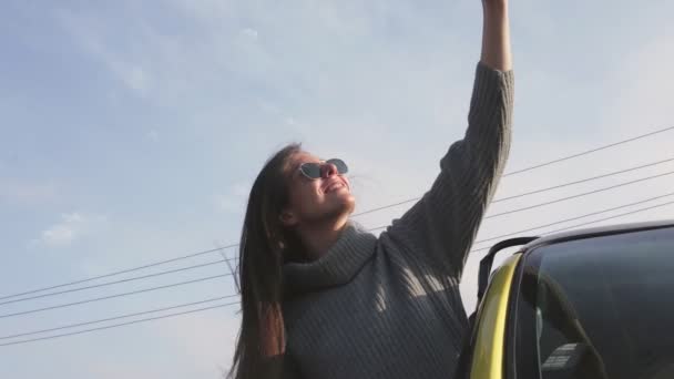 Jeune femme avec des lunettes de soleil penché par la fenêtre de la voiture et enregistre des histoires selfie auto vidéo — Video