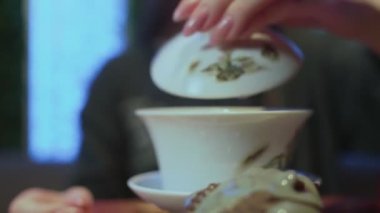 Çay tahtasında Çin çayı pişirmek. Kadın çaydanlıktan fincana çay doldurup içiyor.