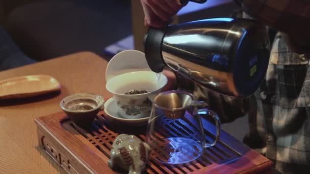 Cocinar té chino en una mesa de té. Mujer vierte agua caliente de la tetera a la taza con té chino — Vídeo de stock