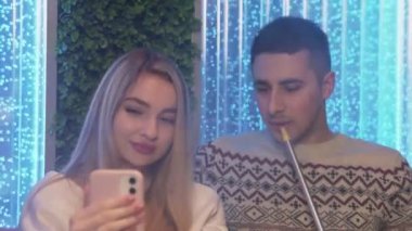 Genç çiftler nargile içer ve Shisha 'nın salonunda selfie çeker.