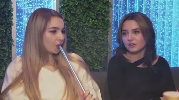 Close up of two female friends in hookah bar. one woman offers to smoke, other woman refuses and drinks tea — Stock Video