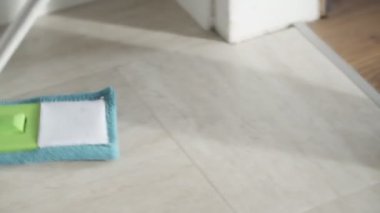 Genç bir kadının beyaz mutfak zeminini sprey ile silmesi, temizlik hizmetleri...