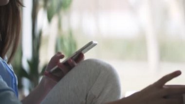 Genç, güzel esmer kadın mutfakta oturuyor, telefon ediyor ve sabah kahvesini içiyor.