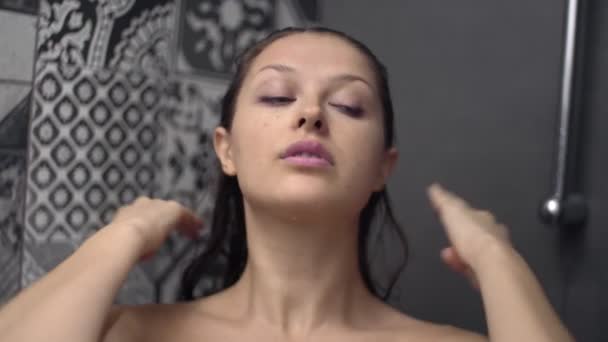 Uzun siyah saçlı, duştan sonra ıslak genç bir kadın modern bir banyoda duruyor. — Stok video