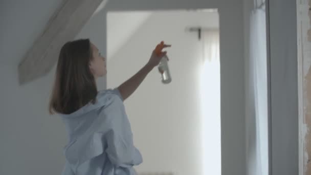 Молода домогосподарка використовує освіжувач повітря вдома — стокове відео