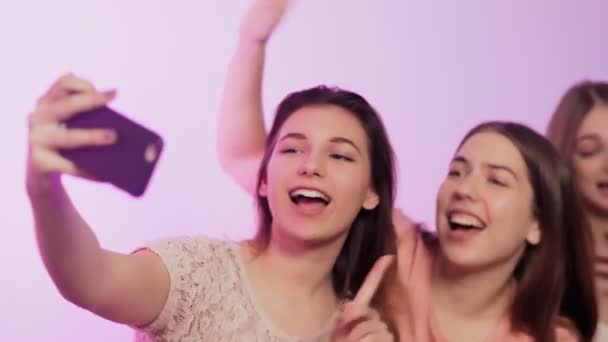 Cuatro hermosas mujeres jóvenes felices en pijama se sienta en la cama, canta y graba vídeo en sus teléfonos en la despedida de soltera — Vídeo de stock