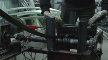 Tanınmayan bir adam metal bir çubuğu bükmek için makine kullanıyor.