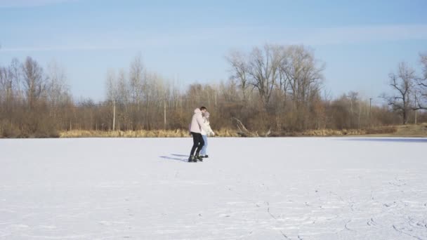 Ungt par rider på skøjteløb sammen på frossen sø i skov – Stock-video