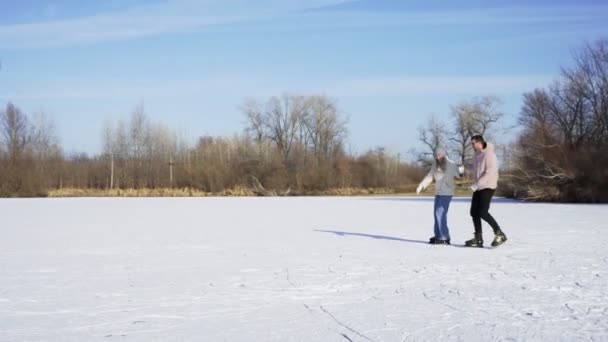 Mladý pár jezdit bruslení společně na zamrzlé jezero v lese — Stock video