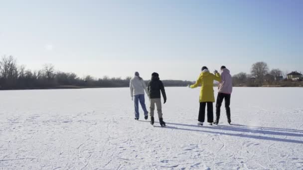 Mladí šťastní přátelé jezdit bruslení společně na velkém zamrzlém jezeře v lese — Stock video