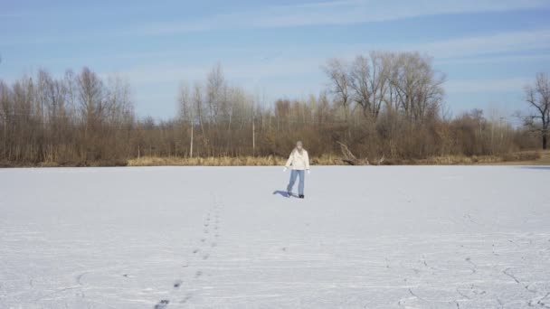 Νεαρή μόνη γυναίκα κάνει πατινάζ στον πάγο στην παγωμένη λίμνη στο δάσος — Αρχείο Βίντεο
