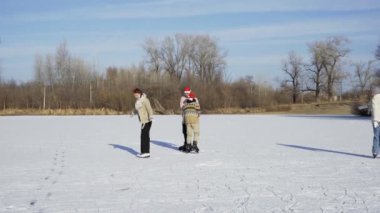 Noel Baba şapkalı dört en iyi arkadaş buz pateni yapıyor ve ormanda donmuş bir gölde birlikte eğleniyorlar.