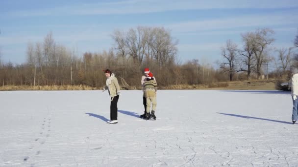 Čtyři nejlepší přátelé v vánoční Santa klobouky jezdit bruslení a bavit se společně na velkém zamrzlém jezeře v lese — Stock video