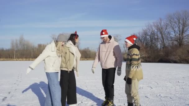 Czterech przyjaciół w Boże Narodzenie Santa kapelusze pozostaje razem i próbuje zrobić sobie selfie przez telefon po przejażdżki na łyżwach na dużym zamarzniętym jeziorze w lesie — Wideo stockowe