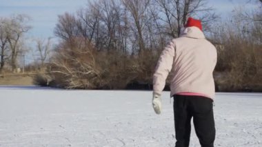 Genç mutlu arkadaşlar ormanda büyük donmuş bir gölde birlikte buz pateni yapıyorlar.