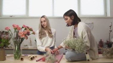 Çiçekçide iki kadın çiçekçi. Çiçek tasarım stüdyosunda güzel ve şık bir çiçek buketi yapan kadınlar..