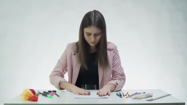 Atractiva joven mujer hace un avión de papel en la mesa en un estudio blanco — Vídeo de stock