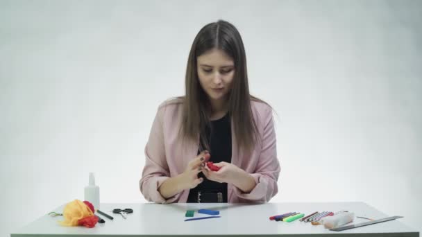 Atraktivní mladá žena hraje s plasticínou u stolu v bílém studiu — Stock video