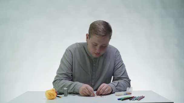 Młody mężczyzna paciorkowiec bransoletka przy stole w białym studio — Wideo stockowe