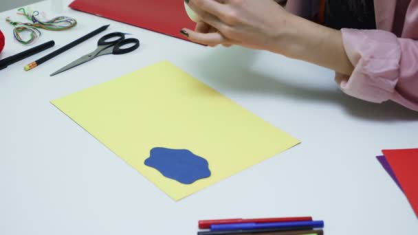 Primer plano de la mujer pega una nube hecha de papel de color a una hoja amarilla en la mesa — Vídeos de Stock