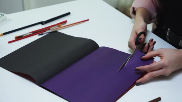 Blisko kobiety używa nożyczek do cięcia linii kolorowego papieru przy stole — Wideo stockowe