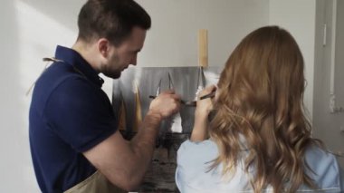 Genç mutlu çiftler resim stüdyosunda resim çizerler. Renk ve folyo kullanıyorlar.