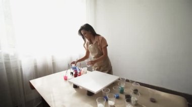 Genç, güzel kadın sanatçı, renkler hazırlıyor ve akışkan sanatın resmini çiziyor.