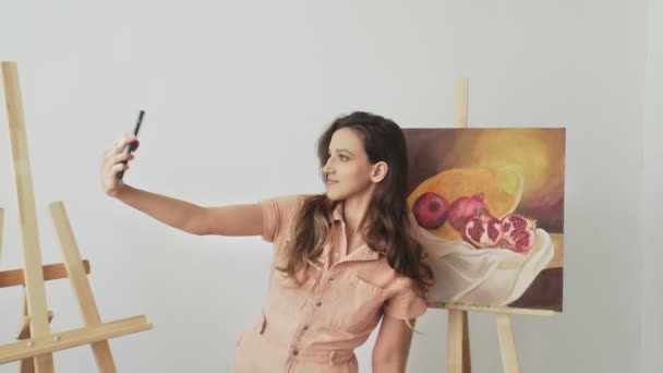 Belle artiste prend une photo avec elle une nouvelle photo à son atelier — Video