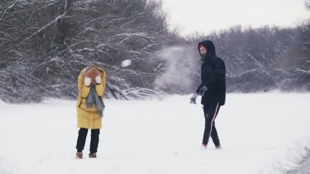 Glückliches junges Paar spielt mit Schneebällen im Winterwald — Stockvideo