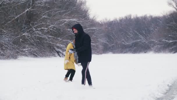 Jovem casal joga com bolas de neve na floresta de inverno — Vídeo de Stock