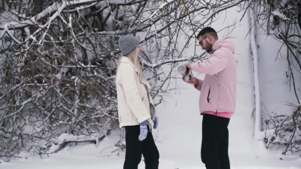 Jeune homme verse le thé d'un thermos à sa petite amie — Video